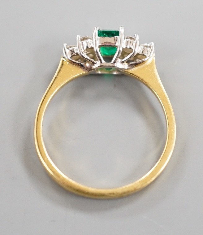 A modern 18ct gold and single stone emerald ring, with six stone diamond set shoulders, size N, gross weight 3.2 grams